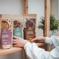 Deux mains qui prennent des sachets de granola sur une étagère