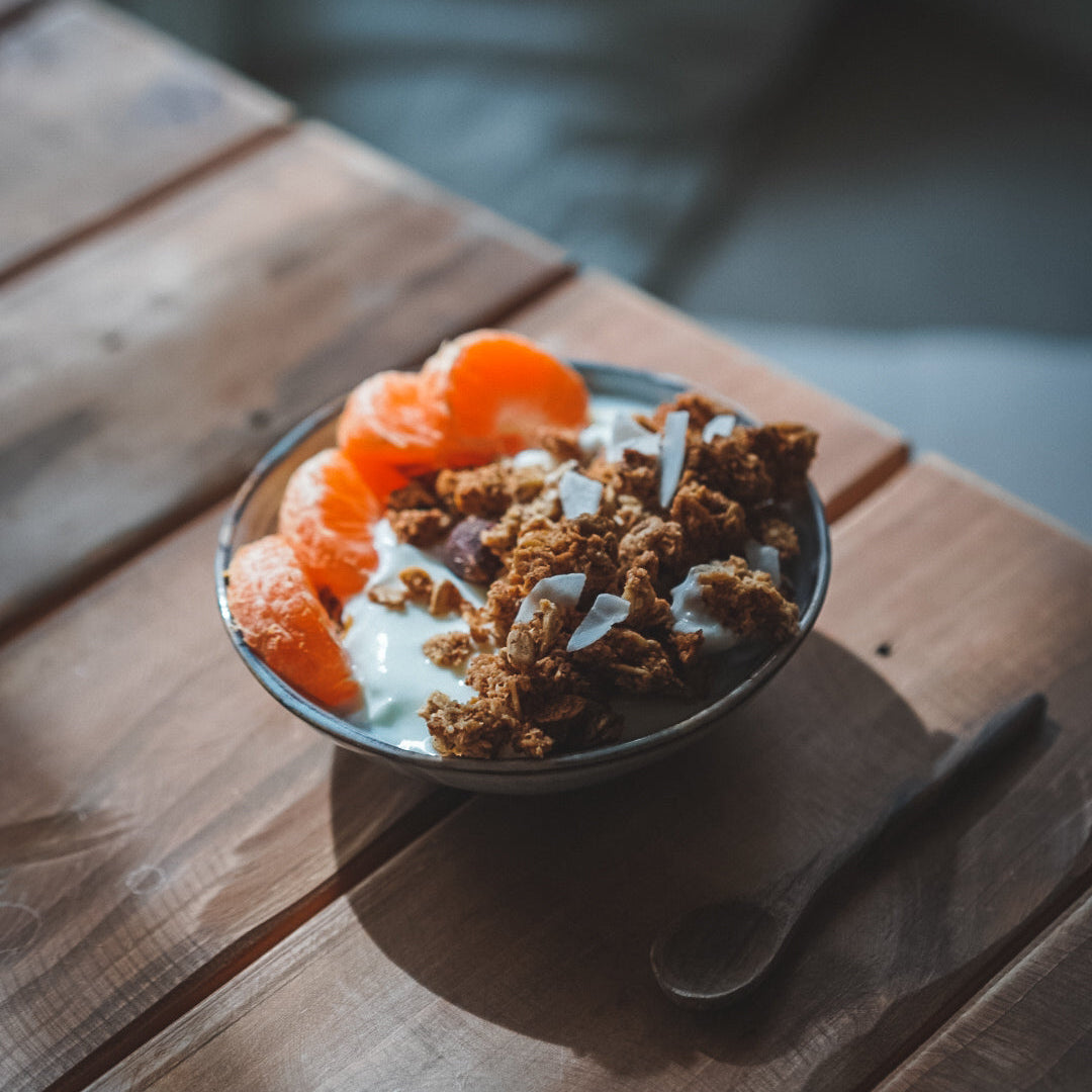 Un bol de granola à la noix de coco avec des quartiers de clémentine sur une table en bois